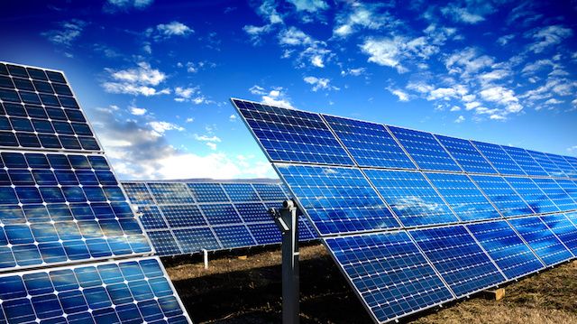 Rows of photovoltaic solar panels and blue sky with clouds